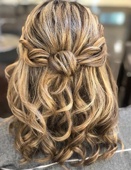 Half-up half-down hairstyle with braided sides and loose curls.
