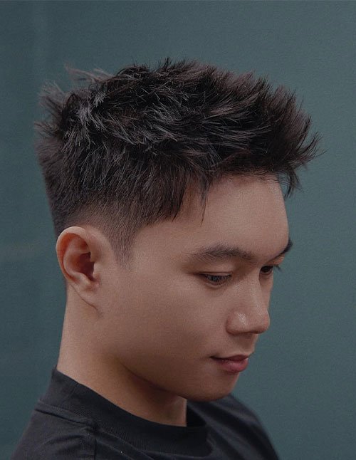Man with Ivy League base cut featuring a tousled textured top and short tapered sides.