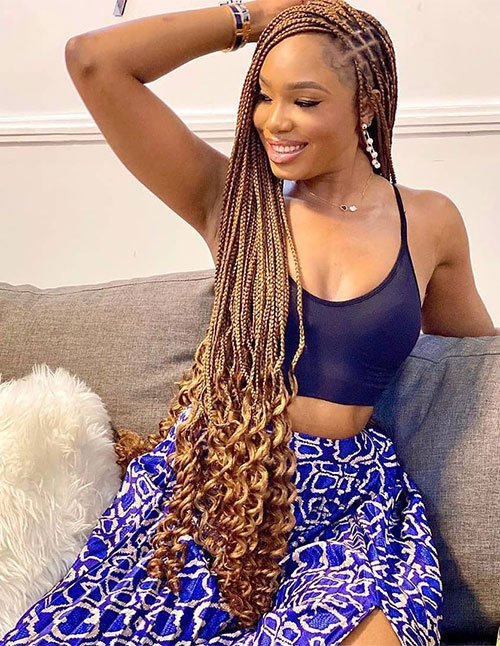 Long knotless braids styled to one side, with curly ends for a soft, voluminous finish.