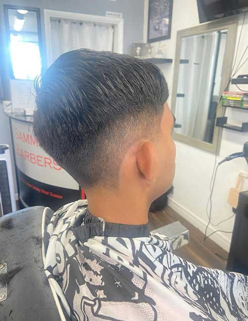 Long drop fade haircut with longer hair on top and a smooth fade that drops lower behind the ear.