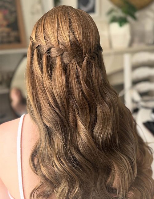 Loose waterfall braid on long, softly wavy light brown hair.