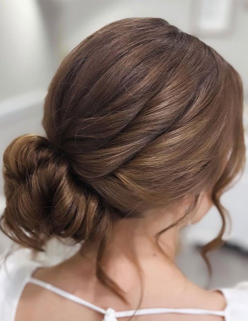 Elegant low bun winter hairstyle with soft texture and loose face-framing strands