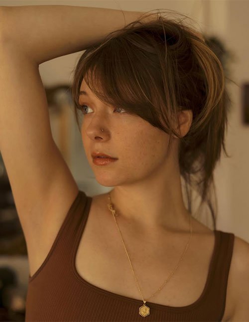 Woman with low-commitment wispy bangs and a casual messy updo.