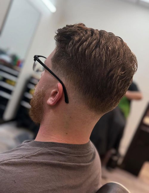 Low fade with flow haircut featuring a clean low fade and longer wavy hair on top styled back for natural movement.