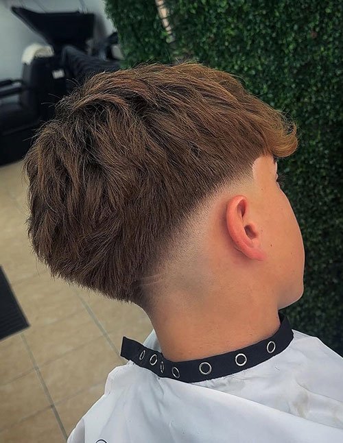 Low skin fade haircut with hair faded down to the skin at the neckline and sides, leaving a fuller top.