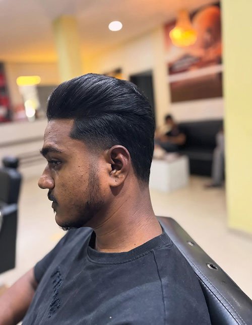 Side profile of a man with a low taper fade haircut, featuring neatly tapered sides and a clean, natural transition into a longer, slicked-back top.