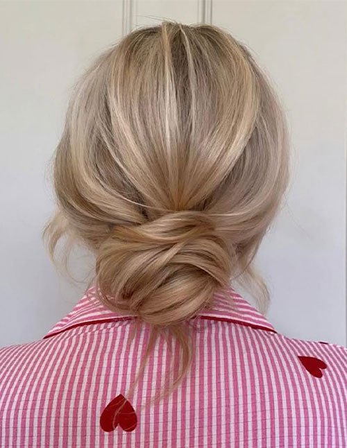 Back view of blonde hair styled into a low twisted bun at the nape, with softly gathered sections creating a smooth and relaxed finish.