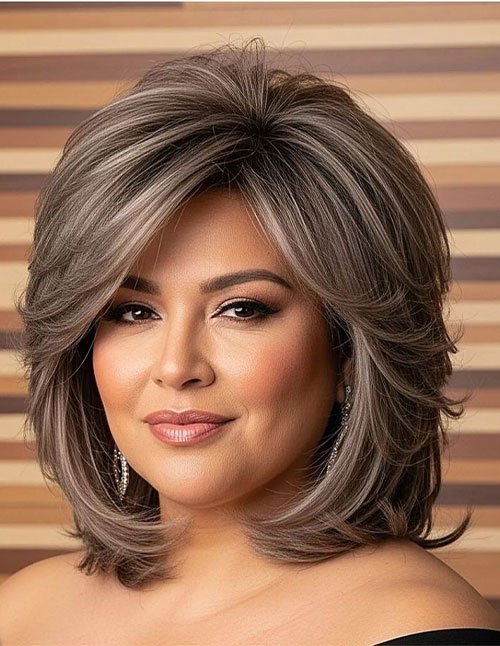 Front view of medium bob with soft layered ends, side-swept volume, and ash-brown highlights