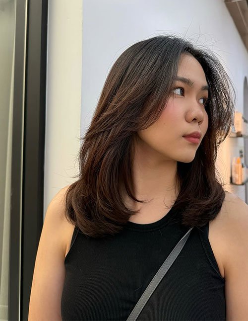 One woman with a medium-length haircut featuring short layers, styled with soft volume and a natural side part.