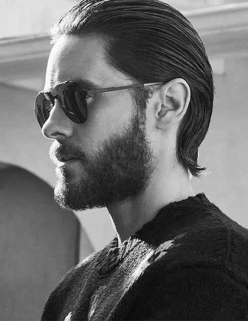 Medium slick back hairstyle with hair combed straight back, natural volume at the crown, and a neat tapered neckline.