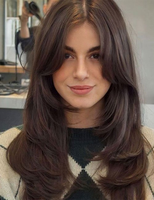 Woman with medium-length straight hair styled with soft face-framing layers and smooth volume.