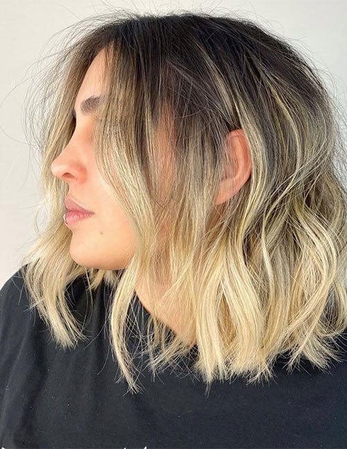 Side-profile of one woman with medium-length hair cut in soft layers, dark roots blending into blonde ends.