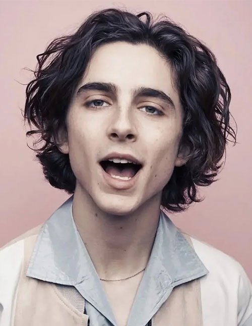 Man with medium wavy hair, showing natural waves and soft movement around the face.