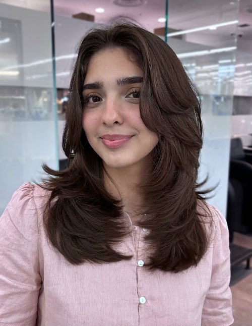 Woman with medium-length butterfly layered haircut featuring soft, airy, face-framing volume.