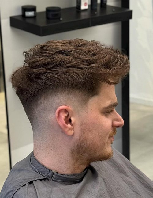 Messy fringe cut with a textured top and a clean fade on the sides for a modern, relaxed look.