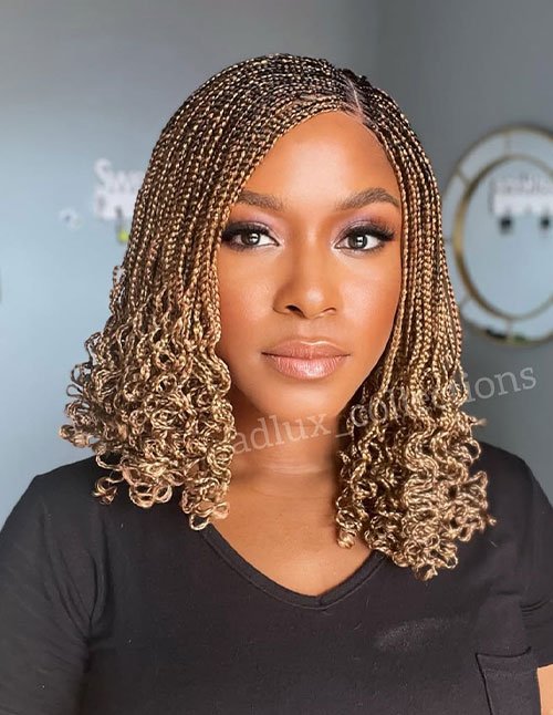 Shoulder-length micro braids with honey-blonde color and tight curly ends.
