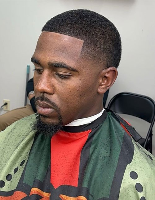 Man with a mid taper fade haircut featuring a sharp lineup and crisp edges, shown in a barbershop chair.