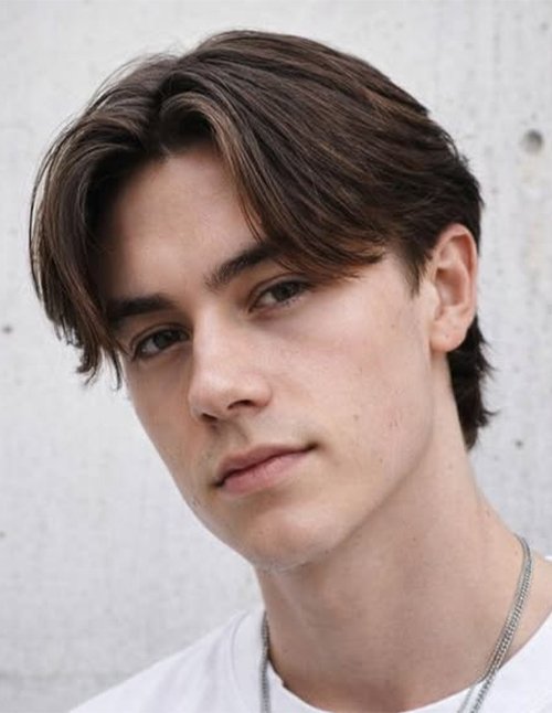 Young man with a middle-part hairstyle and short back, featuring softly layered front pieces that frame the face with a clean, modern finish.