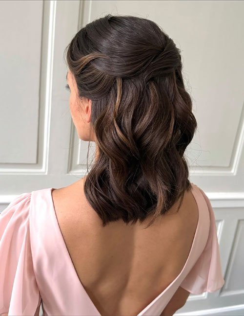 Minimal half-up wedding hairstyle on short wavy brunette hair.