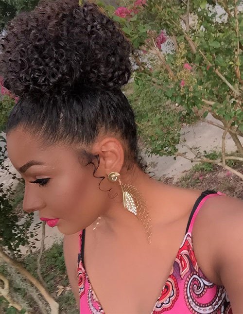 Natural curly high puff bun with a sleek base and soft baby-hair curls.