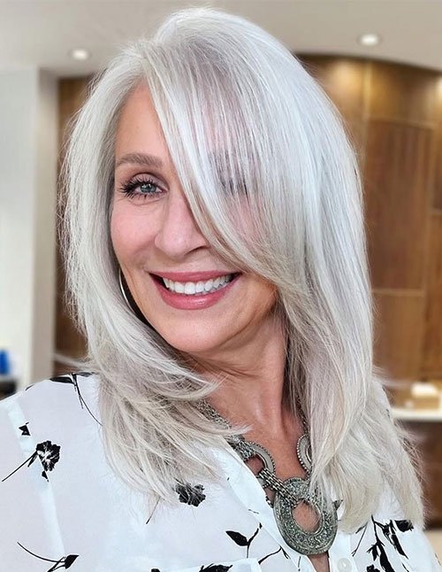 Polished lob haircut with deep side swoop and sleek silver-blonde finish