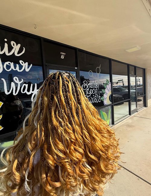 Pretty golden braided style with small braids at the crown that blend into loose, wavy curls, creating a long half-braided goddess look.