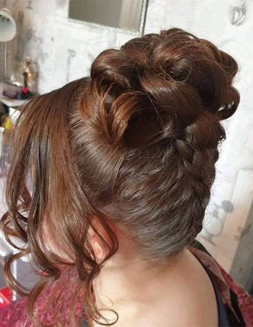 Textured prom updo on short hair with a voluminous bun and loose curled bangs, side view.