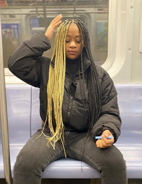 Protective golden knotless braids with a middle part and dramatic half-blonde, half-black split color, styled in long sleek braids.