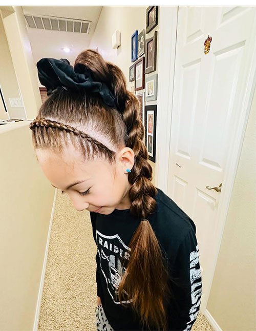 Side view of a girl wearing a quick braided ponytail with a sleek high pony, a small front braid, and a long braided section flowing down.