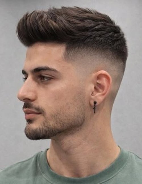 Man with a textured quiff hairstyle featuring faded sides, voluminous hair on top styled upward, and a clean, modern finish.
