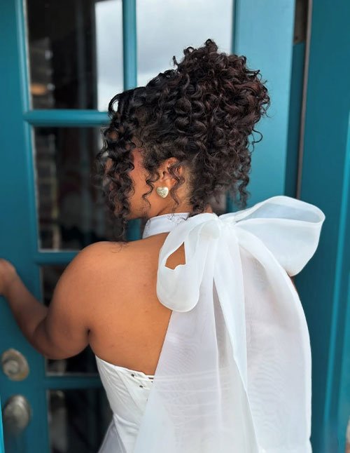 Curly ringlet bun updo with soft face-framing tendrils for bridesmaid