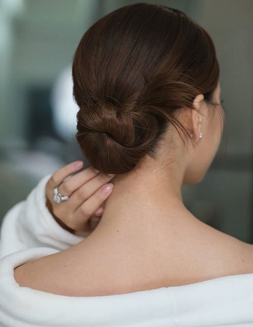 Back view of a short hair chignon styled into a smooth, low bun at the nape with neatly tucked sections.