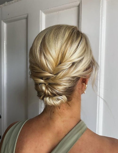 Blonde hair styled into a short low updo with a twisted crown.