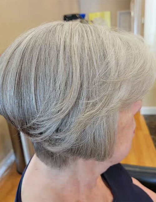 Side view of a short stacked wedge bob in silver-gray hair.
