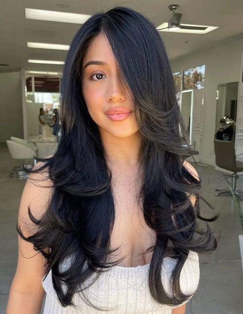 Side-part layers with long, flowing hair and soft face-framing pieces, styled with bouncy layered ends.