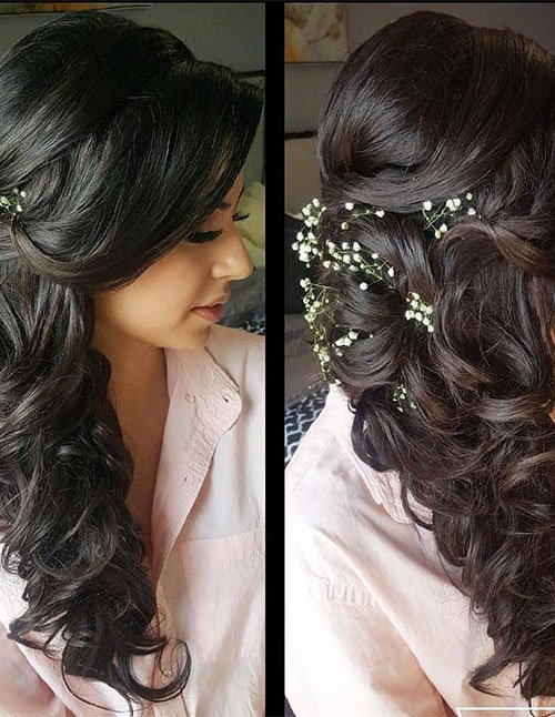 Side-swept curly waves styled to one side with soft volume and delicate floral hair pins.