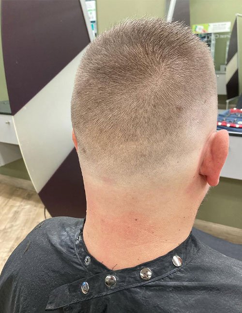 Back view of a man with a simple fade haircut for winter, featuring a short buzzed top and a smooth low fade blending into the neckline.