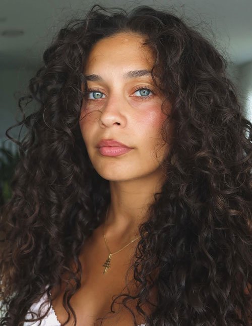 Soft curly side-swept hairstyle with natural volume and loose curls