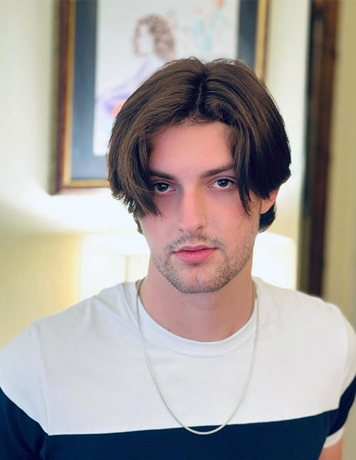 Man with soft curtain bangs featuring middle-parted layered hair framing the face.