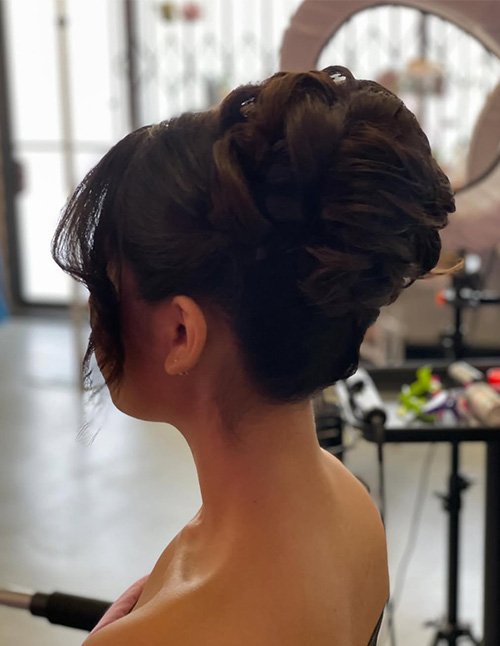 Soft formal updo with a twisted low bun and loose face-framing strands, side view.