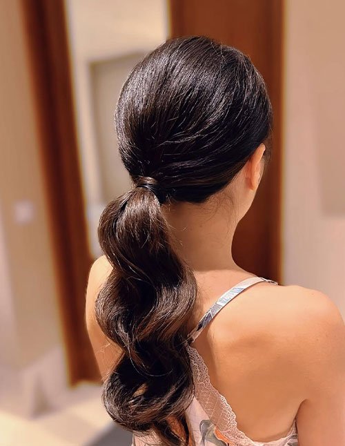 Soft glam low ponytail hairstyle with sleek top and soft wavy length