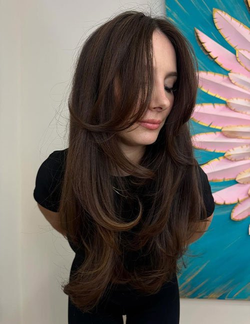 Soft layered blowout with long face-framing layers and smooth, bouncy ends.