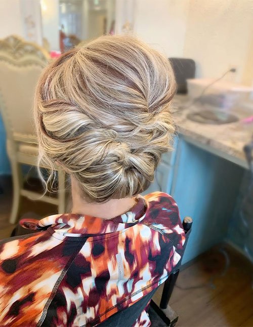 Soft romantic updo with loose twists and a low tucked bun on blonde hair, back view.