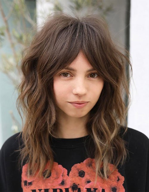 Woman with a soft shag haircut and wispy bangs.