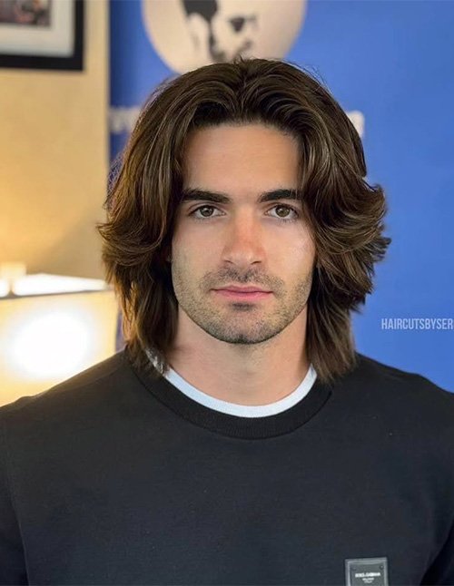 Man with long straight hair styled in a center part, featuring layered flowy sides and feathered ends that frame the face.
