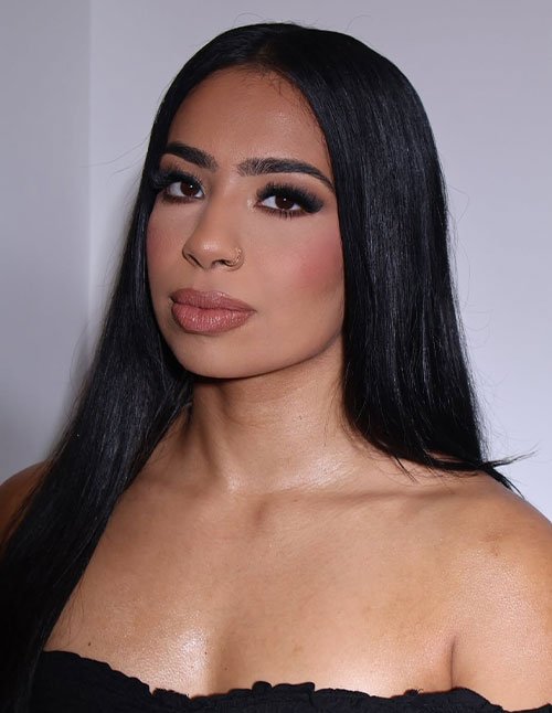 Woman with sleek straight black hair wearing full glam makeup in a studio portrait