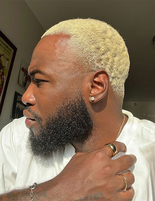 Man wearing a textured Caesar haircut with short, evenly cropped curls and a clean, low fade on the sides.