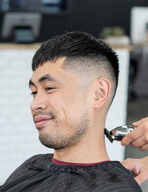 Textured crop fade haircut with short choppy hair on top and a clean low-to-mid fade on the sides.