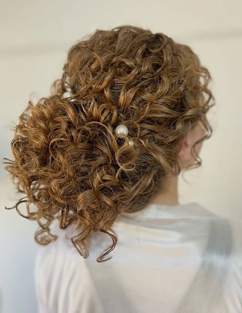 Textured curly low chignon with pearl hair accessory