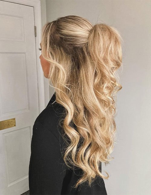 Side view of a textured half-up hairstyle with a softly teased crown and loose curled lengths, creating a messy glam look on blonde hair.